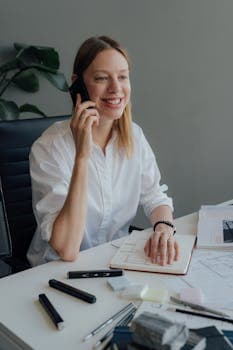 Awomaninawhiteshirtistalkingonacellphone.