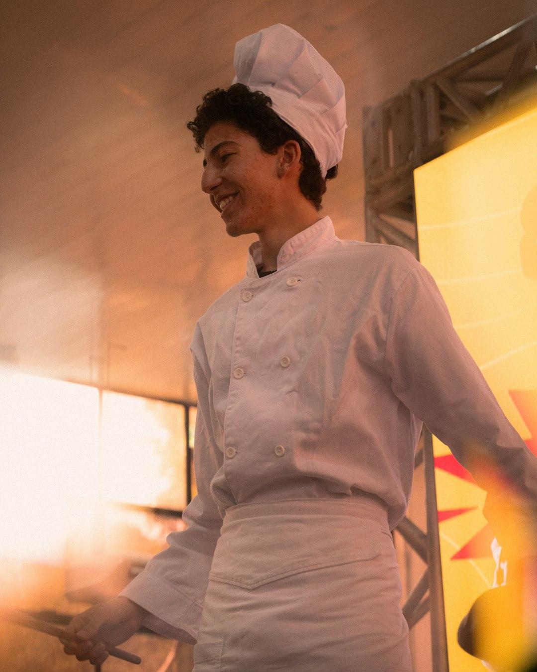 Young chef in white uniform smiles while cooking