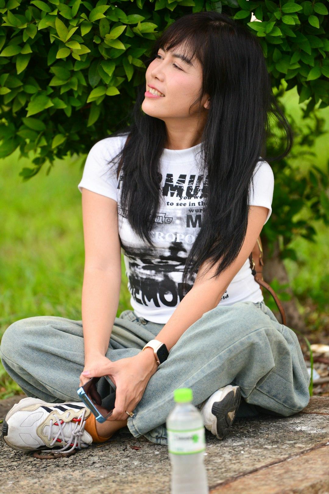 Relaxed Asian Girl Sitting on Pavement with Green Background