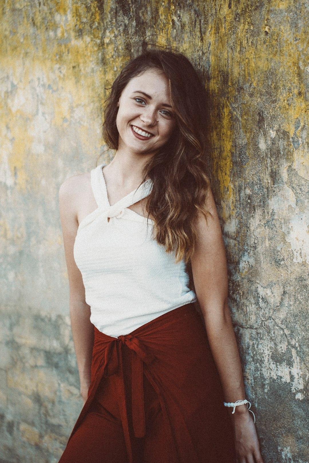 Young woman smiling leaning against textured wall