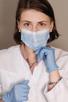Portrait of a female healthcare worker with face mask and gloves, ready for medical care.