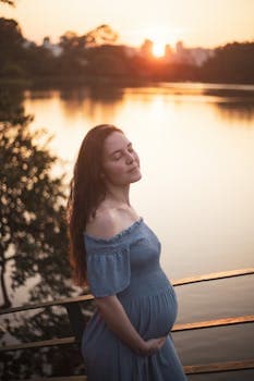 A peaceful image of a pregnant woman enjoying a sunset by the lake, capturing the beauty of motherhood.