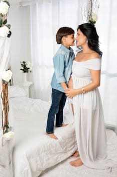 Pregnant woman and child share a tender moment in a beautifully decorated bedroom.