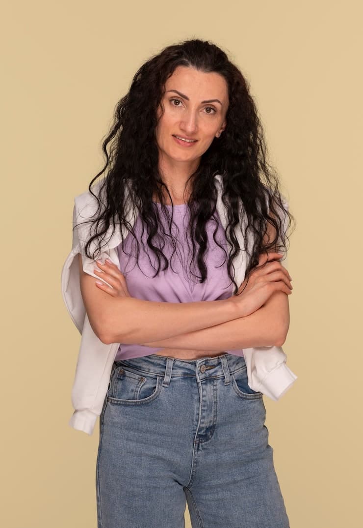 A woman with long black hair is standing in front of a yellow ...