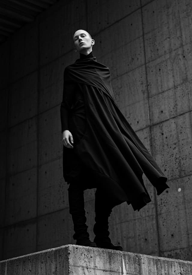 A woman in a black dress is standing in front of a wall, posing for a ...